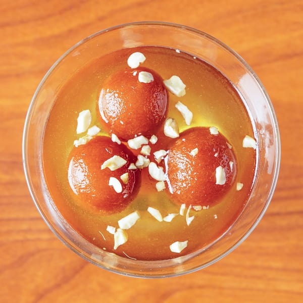 Three gulab jamun, Indian fried dough balls, in syrup and topped with chopped nuts.